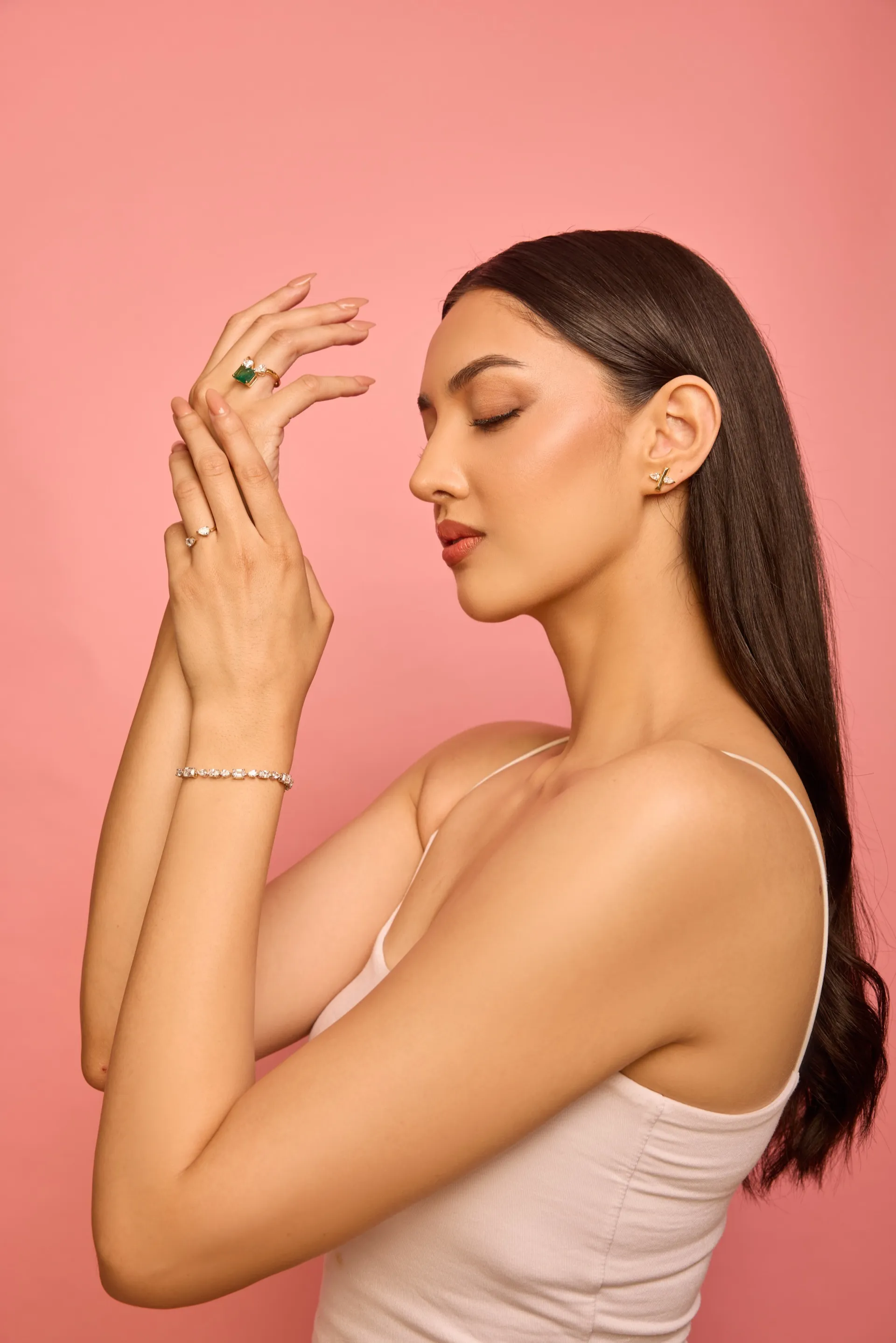 Portrait of a woman with eyes closed, one hand at her chin, wearing Tuisa diamond rings and stud earrings
