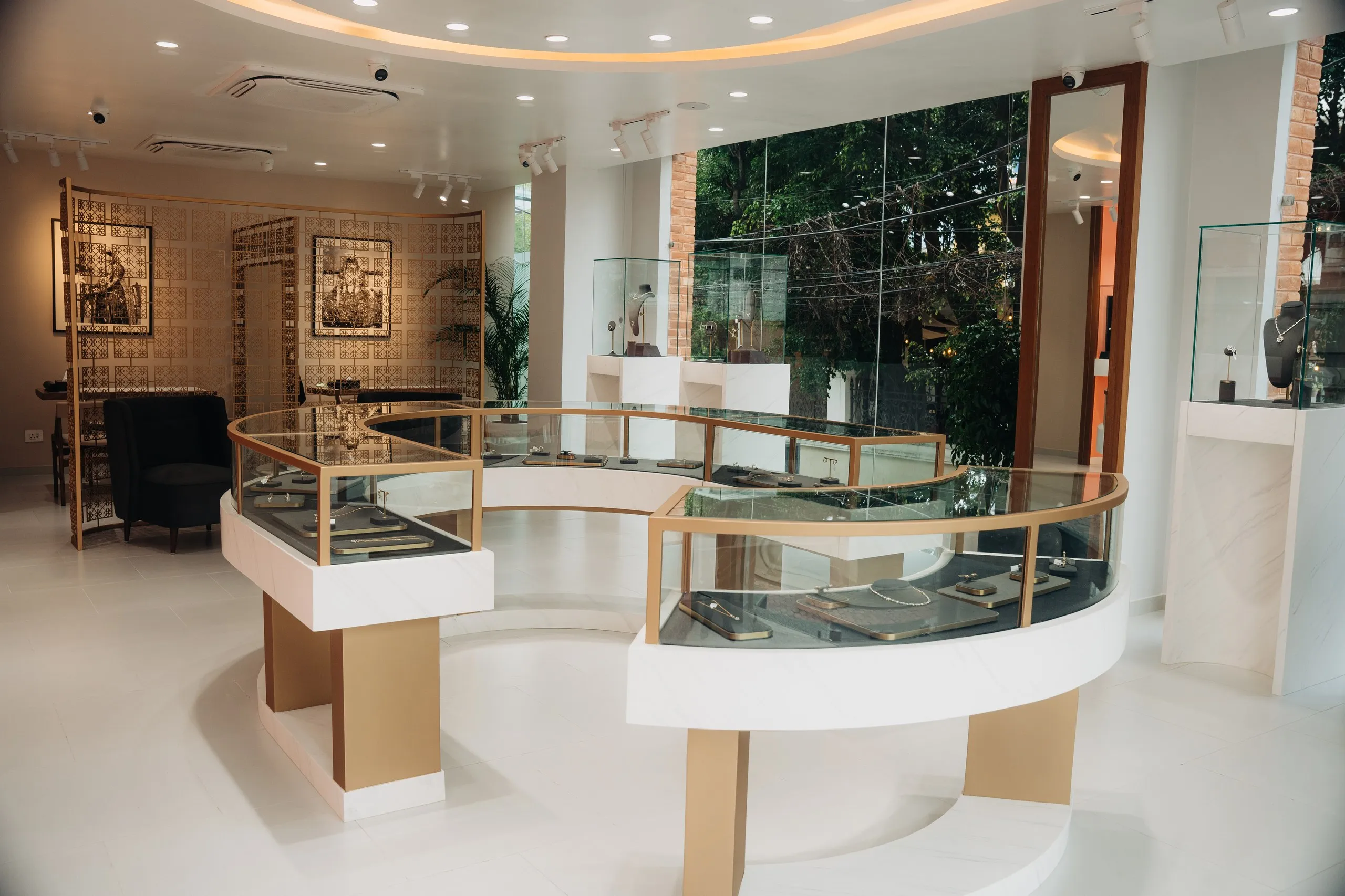 The Tuisa boutique interior in daylight: the brass-edged circular counter on a pale floor, greenery beyond the glass front